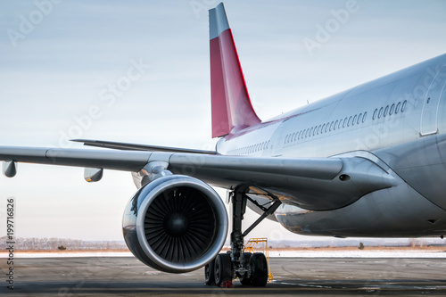 Close-up of wing, engine, main landing gear, fuselage and tail fins of wide-body passenger aircraft