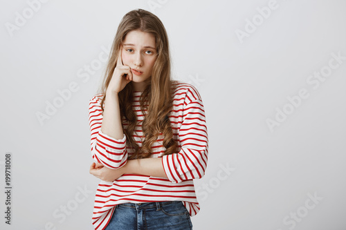 Girl almost sleeps from boredom during class. Portrait of indifferent tired female model supporting head with hand, slouching with drooping eyes, being interested in event, exhausted during date