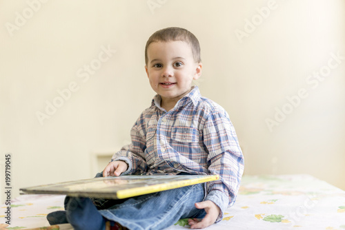 A beautiful little boy is looking at a big book