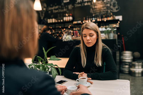 Two girl friends in a cafe having a serious conversation over a cup of coffee