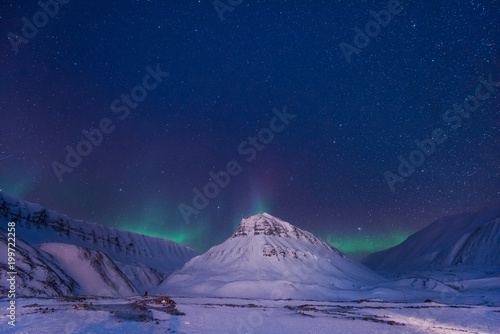 The polar arctic Northern lights aurora borealis sky star in Norway Svalbard in Longyearbyen city man mountains