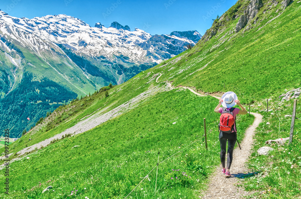 Swiss Alps. A man in a white hat, a traveler in a mountain alpine country walk along the path. Landscape of the Swiss Alps, Engelberg Resort Swiss Alps. A man in a white hat, a traveler in a mountain alpine country walk along the path. Landscape of the Swiss Alps, Engelberg Resort