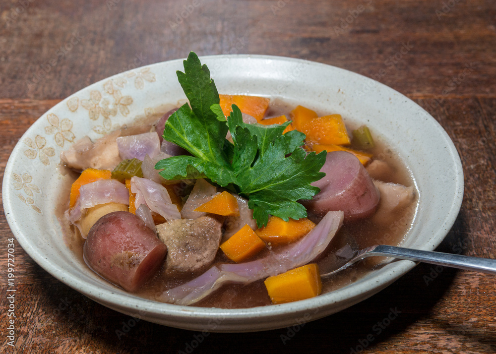 Crockpot stew in tan bowl on wooden table with spoon 