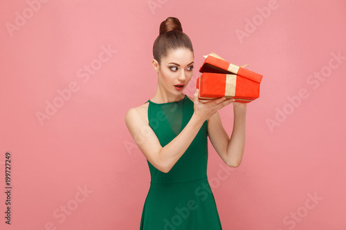Cunning woman unboxing red gift box looking inside photo