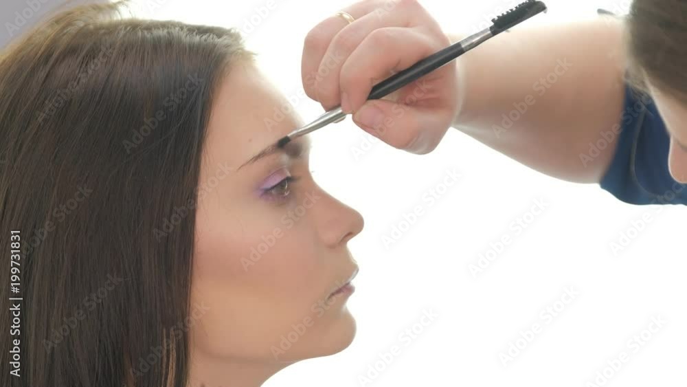 Portrait of young beautiful woman and stylist in make up salon brushing eyebrow Portrait of young beautiful woman and stylist in make up salon brushing eyebrow