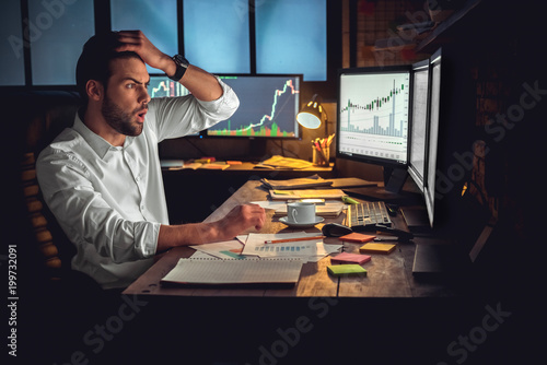 Young male trader at office work concept sitting looking at computer disappointe Fototapet