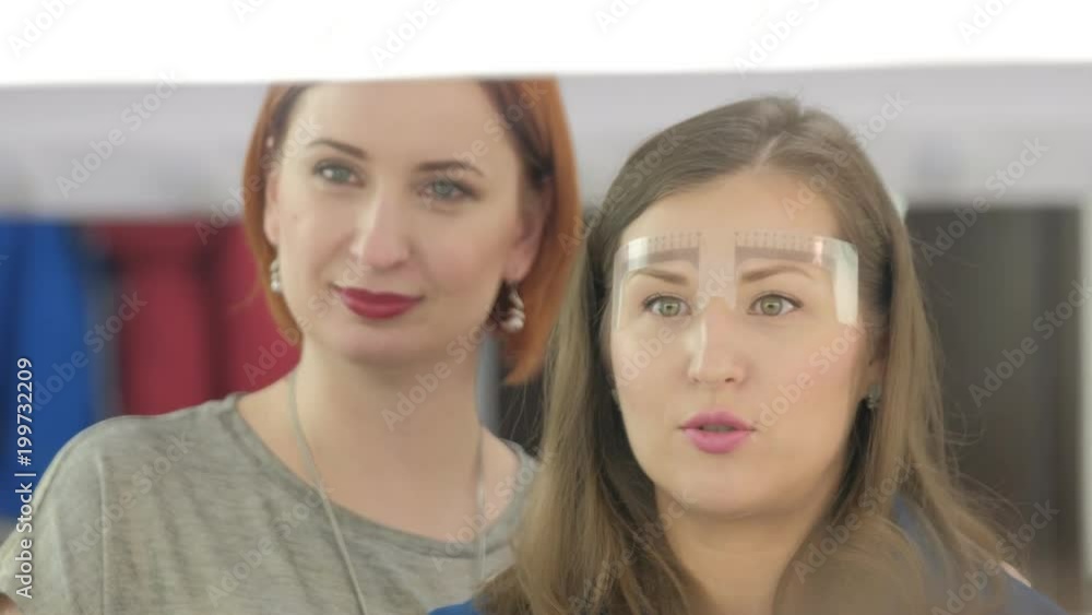 Make up stylists discuss liner on forehead of woman Make up stylists discuss liner on forehead of woman