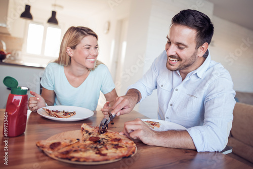 Couple eat pizza in kitchen
