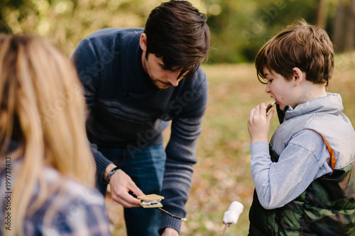 Foto Family making marshmallow s'mores on camping trip