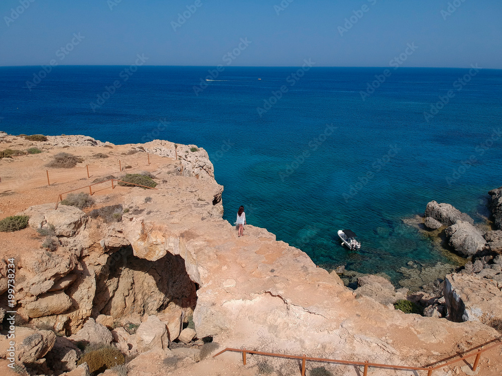 Aerial view of woman standing on natural rock arch over sea