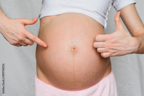 pregnant girl makes a gesture class is a hands on background belly