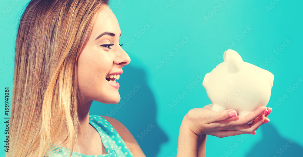 Young woman with a piggy bank on a blue background Young woman with a piggy bank on a blue background