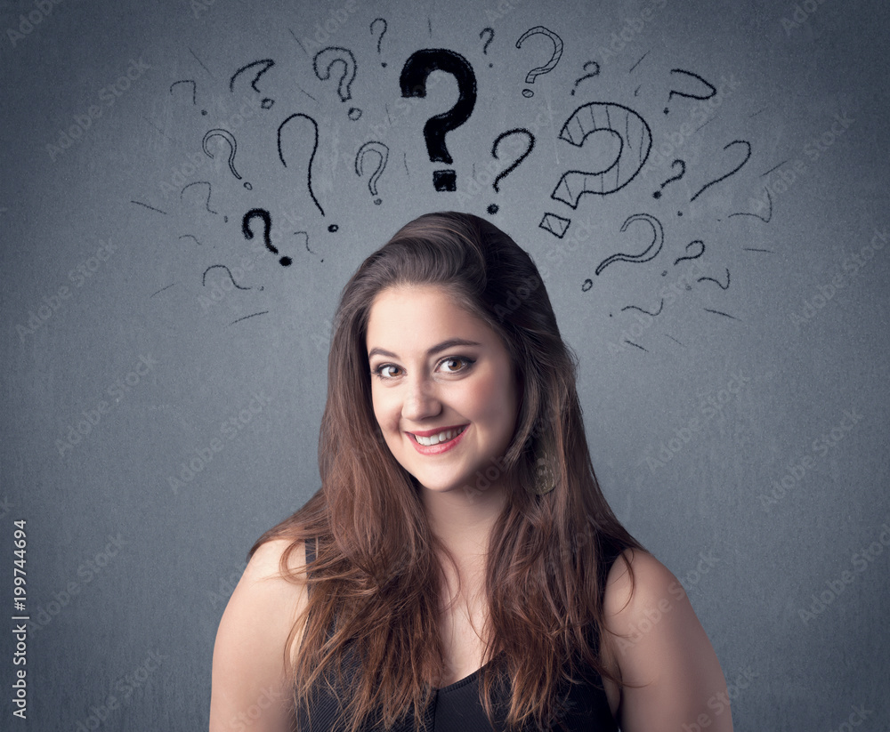 A pretty teenage girl standing confused in front of grey wall background with drawn question marks concept. A pretty teenage girl standing confused in front of grey wall background with drawn question marks concept.