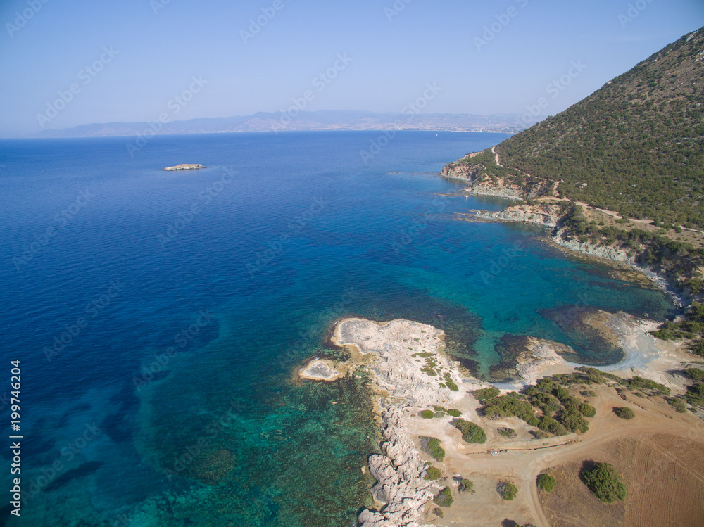 Aerial view of transparent waters beach with cliffs leading up to a mountain