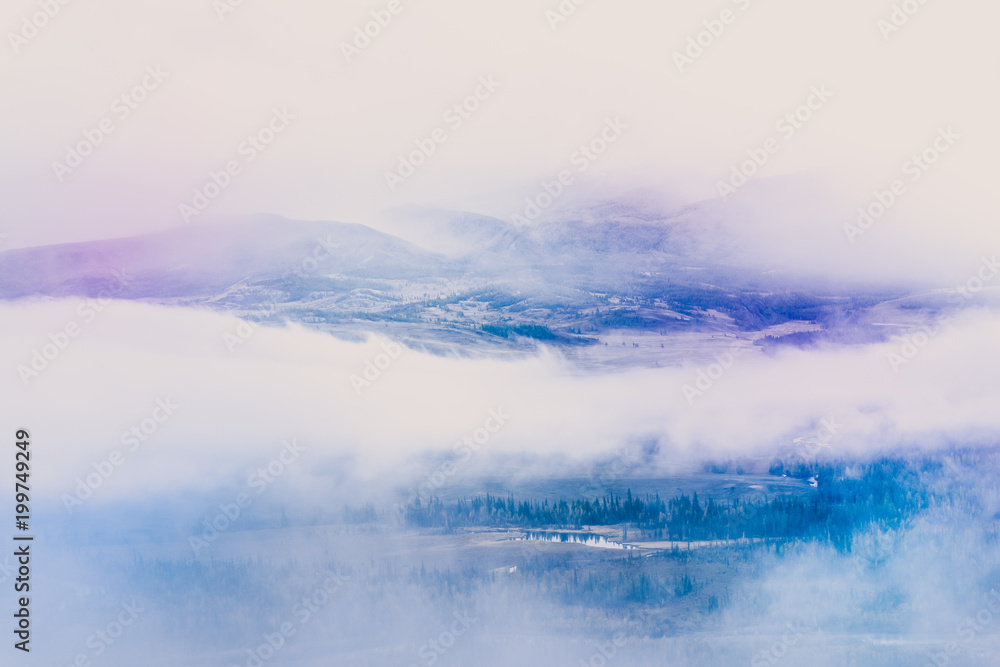 Mysterious view of the hills and canyons in a colorful tone. Mountain peaks in the fog, pastel color.