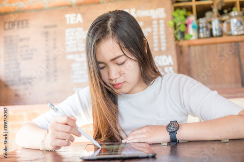 Beautiful young asian women work on the tablet with electronic pen