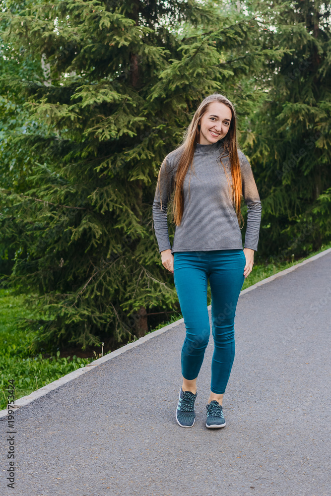 beautiful slender woman in green leggings with long hair standing in the Park beautiful slender woman in green leggings with long hair standing in the Park