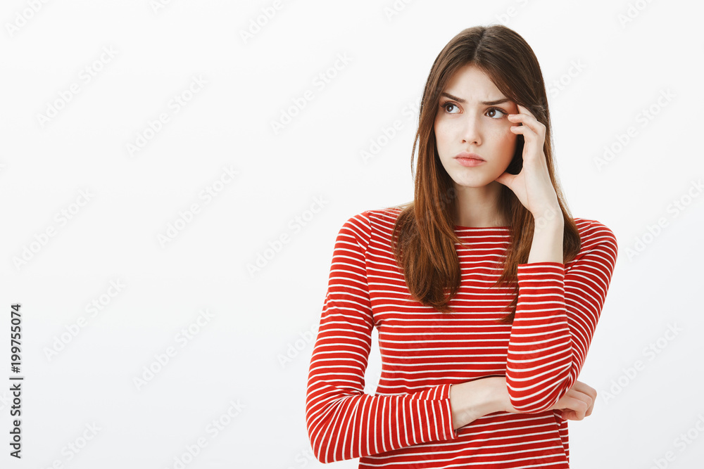 Keep thinking and ideas will come. Portrait of focused attractive smart woman in striped clothes, looking aside and touching temple, carried away with thoughts, recalling important moment Keep thinking and ideas will come. Portrait of focused attractive smart woman in striped clothes, looking aside and touching temple, carried away with thoughts, recalling important moment