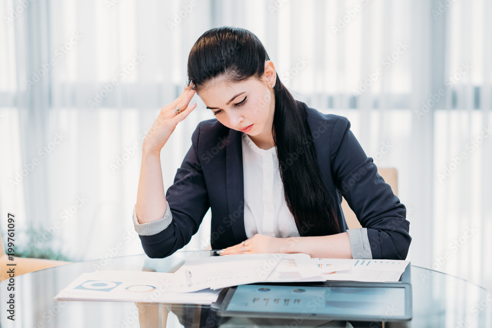 stressed tired business woman. young lady focused on studying report papers and marketing statistics. office workspace stressed tired business woman. young lady focused on studying report papers and marketing statistics. office workspace