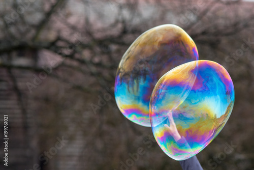 two soap bubbles with hand reaching through to pop them