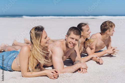 Four young people relaxing in the sun at the beach © contrastwerkstatt