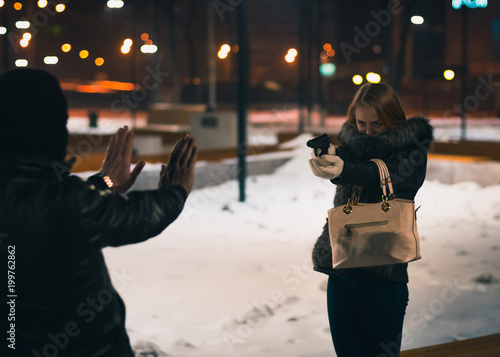 Young Woman pulls a gun from her purse while the villain or thief stood in the back. Self defense concept
