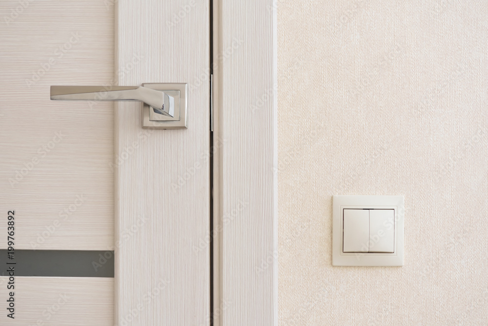 Beige light switch installed next to the door on the wall Beige light switch installed next to the door on the wall