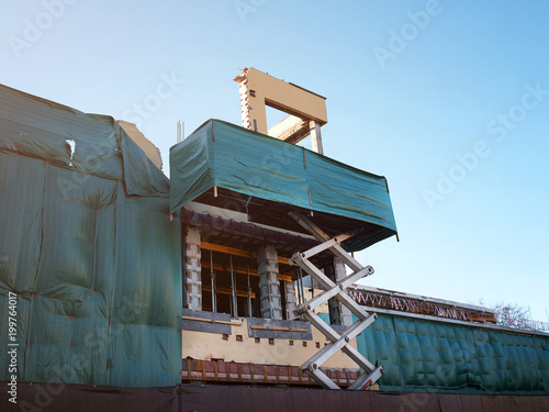 Under constructions. scissor lift holding a wall of a renovating building.  Workers need to strengthen the  old building. Restoration of a monument of architecture photo