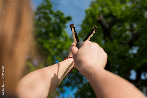 Canvas-taulu Girl shooting from the professional wooden slingshot in the park during a sunny