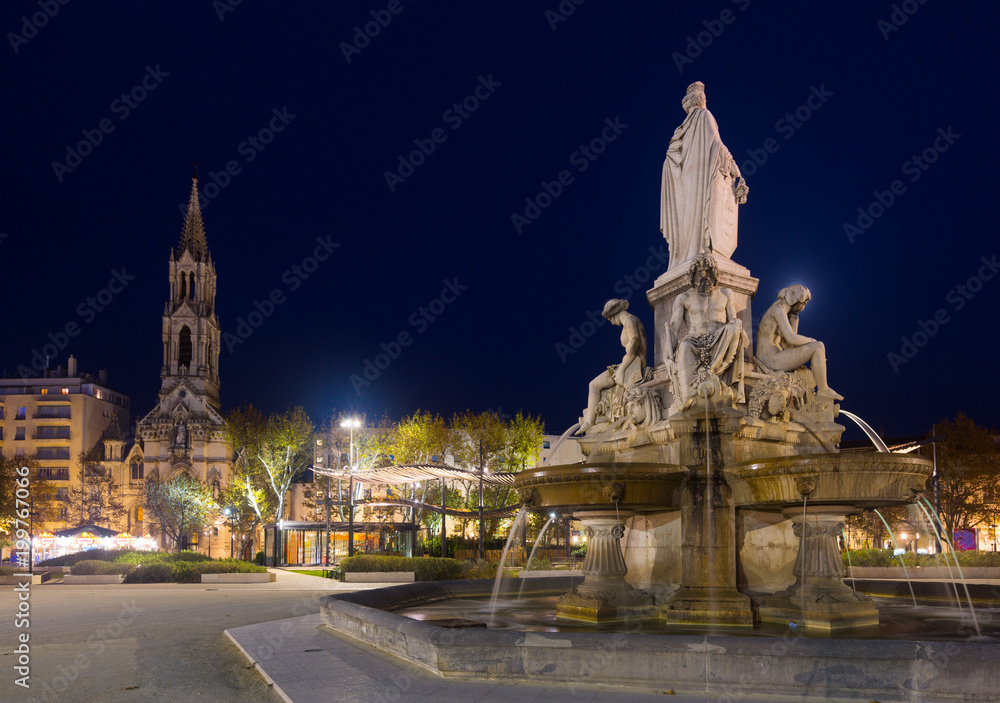 Fototapeta premium Fontaine Pradier illuminated at dusk in Nimes old town