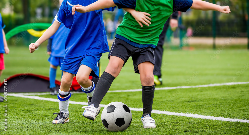 Children play sports. Kids kicking football match. Young boys playing soccer on the green grass pitch. Children play sports. Kids kicking football match. Young boys playing soccer on the green grass pitch.