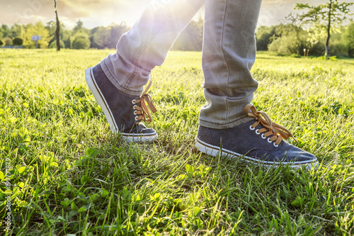 Young person wearing sneakers, walking on the grass
