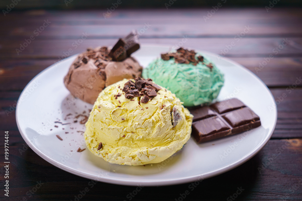 Mint, banana and chocolate ice cream scoops with chocolate crumbs served on white plate, copy space. Delicious refreshing summer sweets, restaurant menu or food background Mint, banana and chocolate ice cream scoops with chocolate crumbs served on white plate, copy space. Delicious refreshing summer sweets, restaurant menu or food background