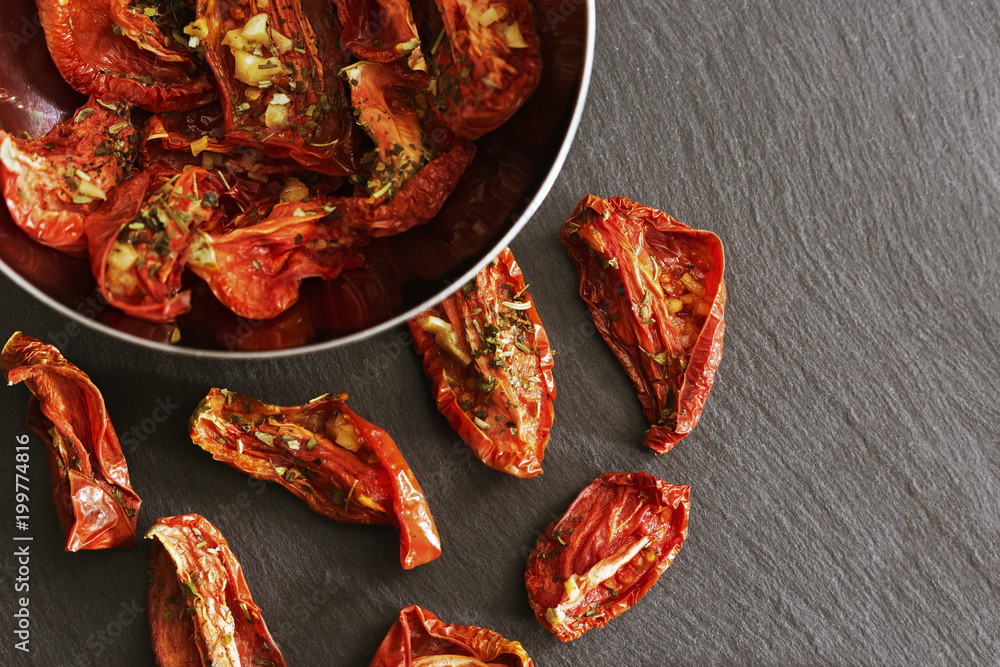 Red dried slices of tomato in metal bowl on dark background. Selective focus. Copy space. Homemade sundried pomodoro. Healthy food. Red dried slices of tomato in metal bowl on dark background. Selective focus. Copy space. Homemade sundried pomodoro. Healthy food.