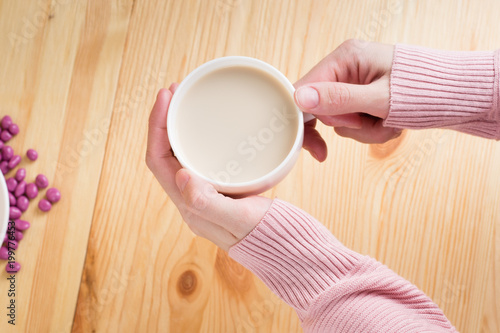 female hands holding coffee with milk on a wooden background