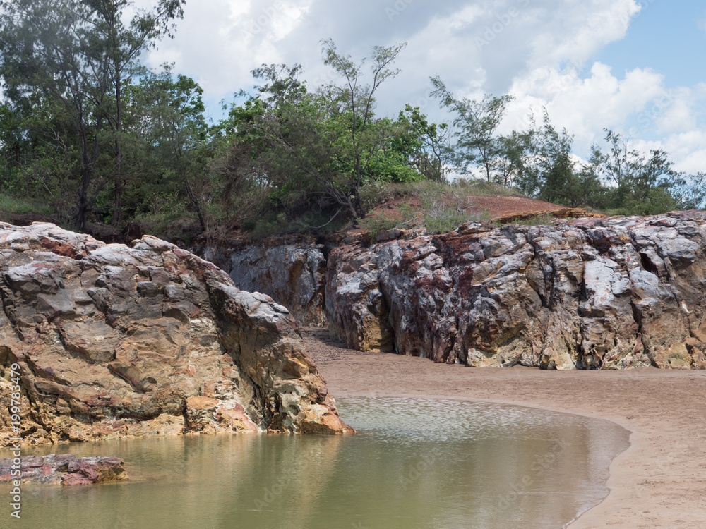 Two cliffs and tidal pool on tropical beach