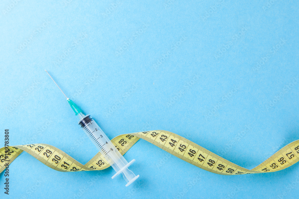 Syringe with a needle and yellow measuring tape. Injections for body