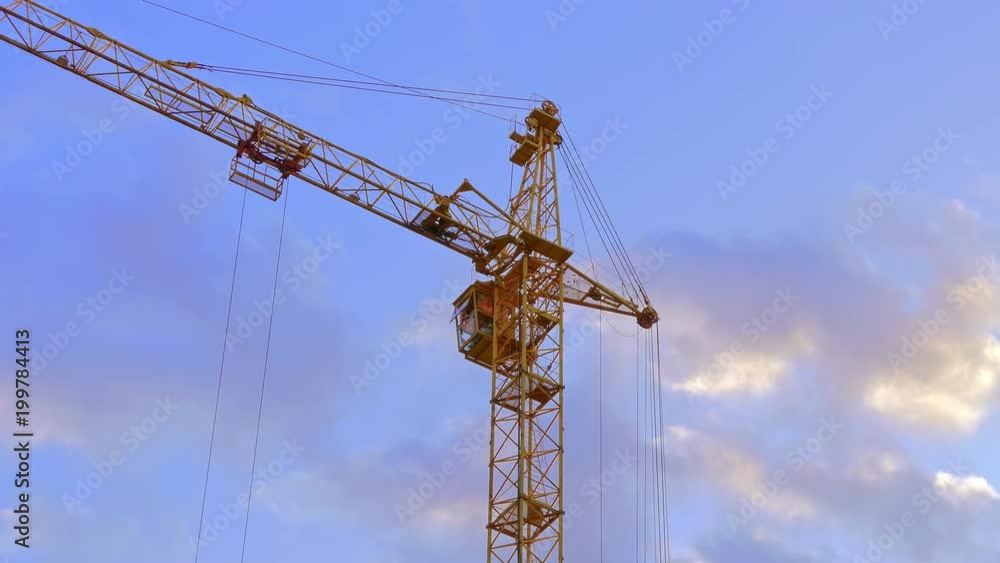 Tower crane / Crane building / Construction site. High tower crane working on the background of the summer sky with clouds. Tower crane / Crane building / Construction site. High tower crane working on the background of the summer sky with clouds.