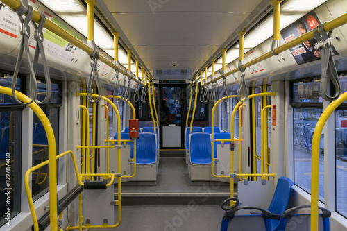 Tram inside, city transportation interior with blue seats yellow handles, bright lights and air conditioner