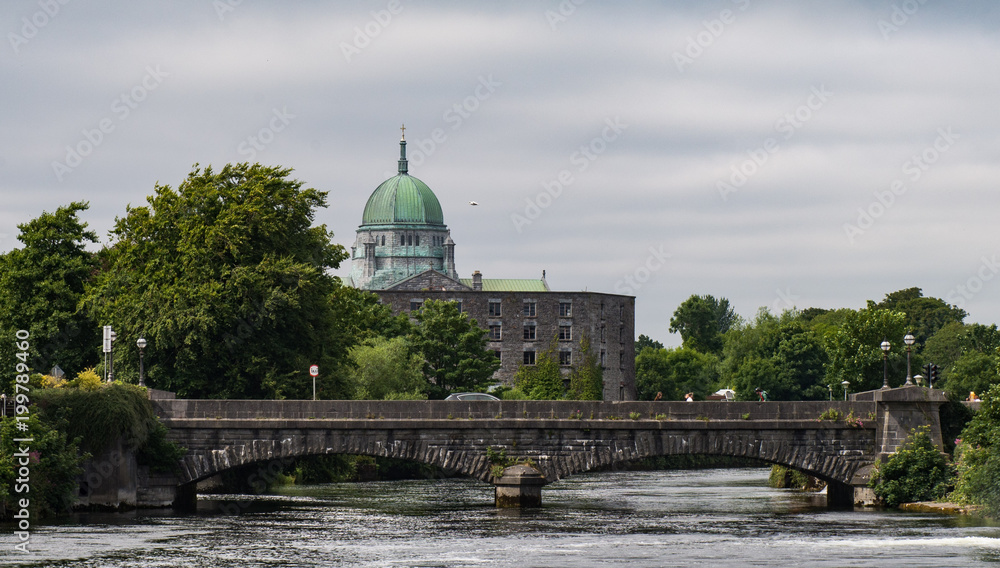 View of Dome of Galway city Cathedral and historic stone bridge crossing in the distance.