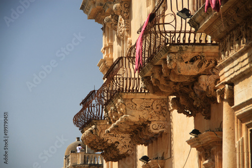 bogato zdobione barokowe balkony na kamiennej elewacji zabytkowego budynku w mieście noto sycylia