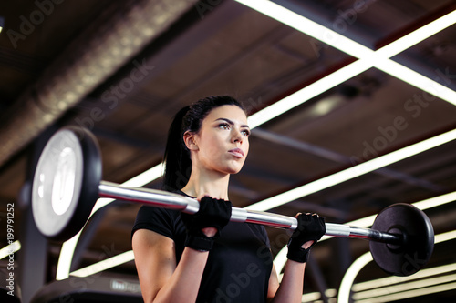 athletic woman pumping up muscules with barbell