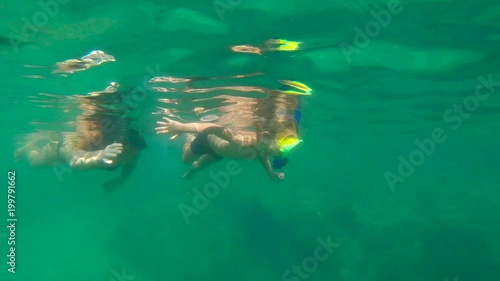 Slowmotion shot of a young woman and her little son snorkeling in a sea photo