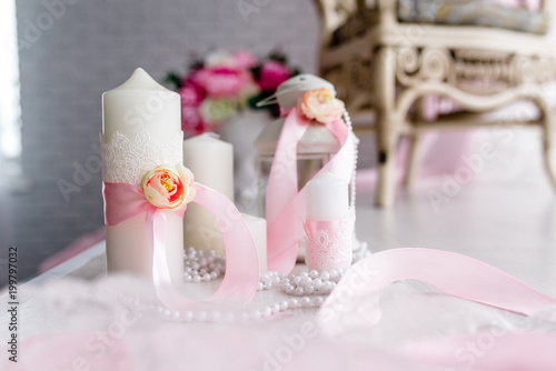 Candle are decorated with pink bow, ribbon and greens stand on the festive table newlyweds covered with a tablecloth. flat lay. top view. Wedding inspiration. Close up. Artwork. Decor. Details. photo