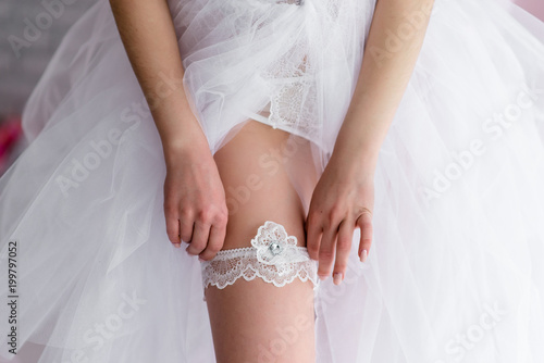 Foto Bride wearing wedding garter. A woman demonstrates her sexy legs