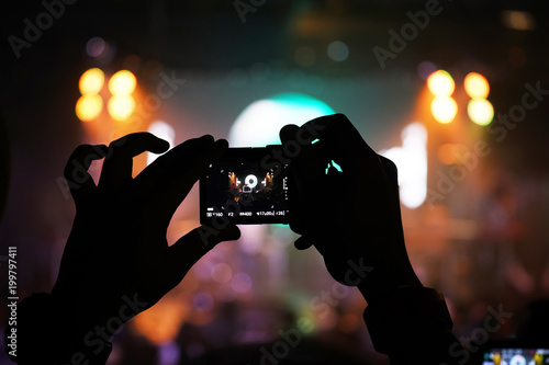 Audience keep taking photo and video at concert with their cellphone focus on the screen with blur background © KoKiChs