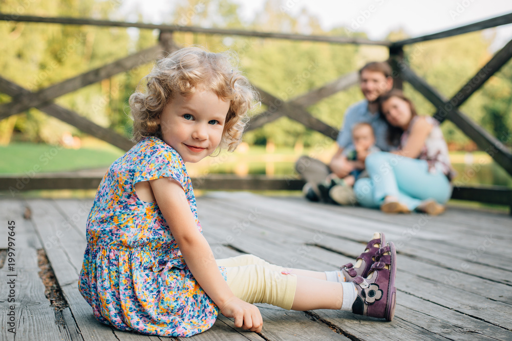 Happy smiling Family Sitting On Wooden Jetty having fun and playing. Parents with cute kids outdoors Happy smiling Family Sitting On Wooden Jetty having fun and playing. Parents with cute kids outdoors
