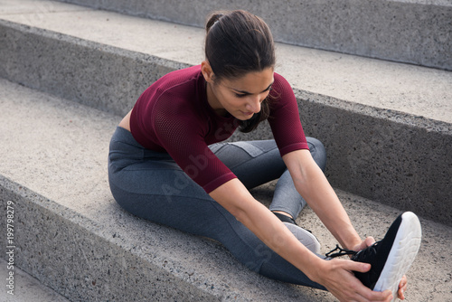 Pretty fit female doing stretches on stairs