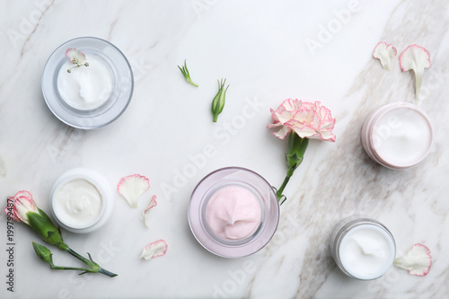 Jars with different body cream on marble background