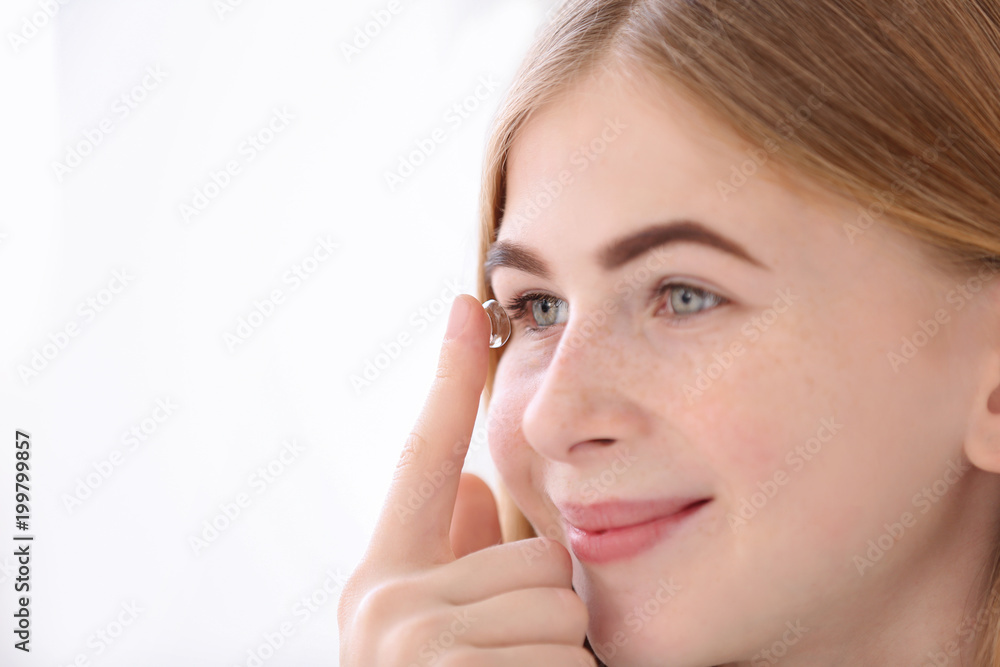 Teenage girl putting contact lens in her eye on white background Teenage girl putting contact lens in her eye on white background
